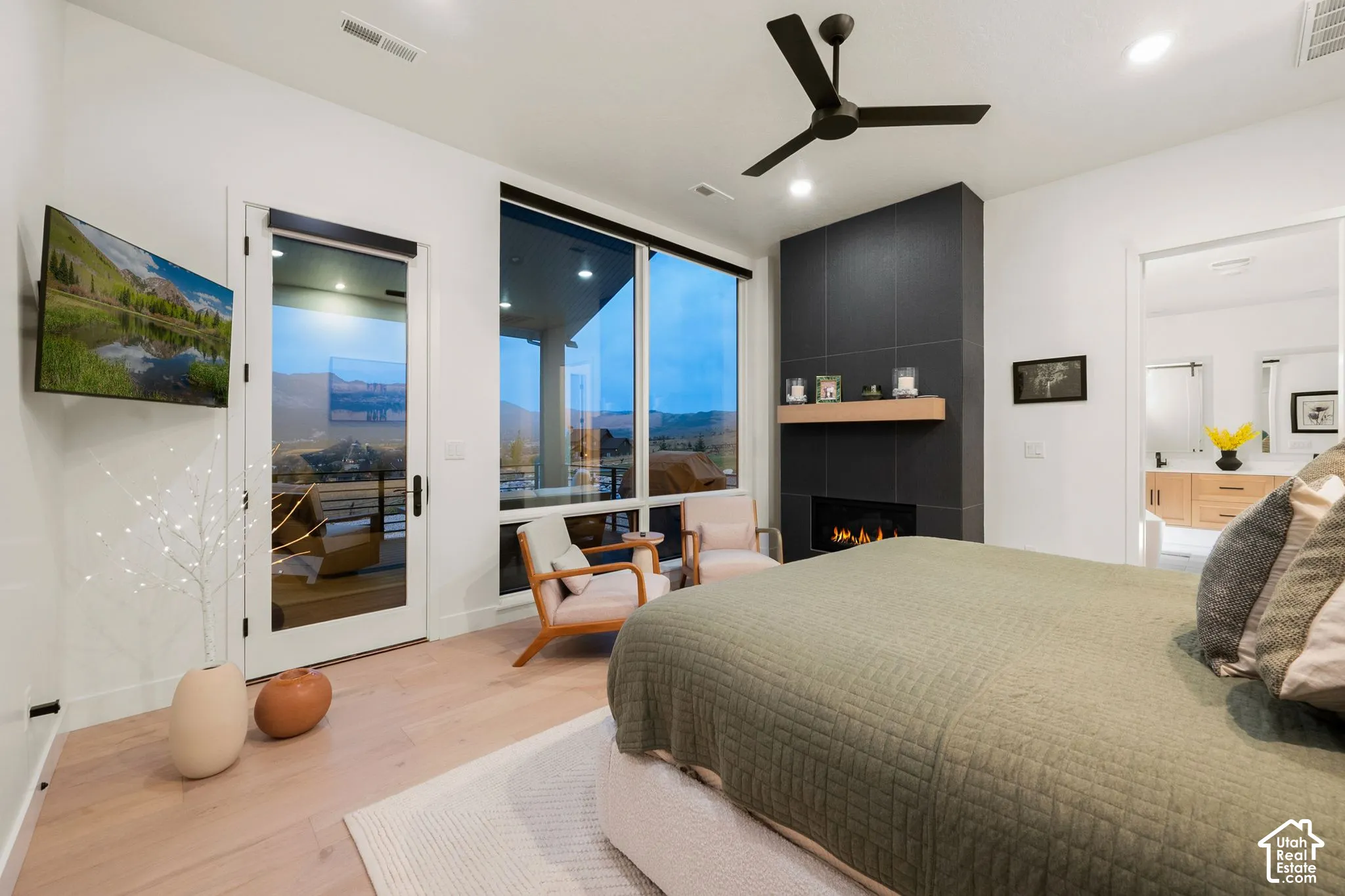 Primary Bedroom Suite with Expansive Glazed Doors and FireplaceThis light-filled bedroom features floor-to-ceiling glass doors opening to a covered exterior space, abundant natural light, and a striking black fireplace accent wall with integrated shelvi