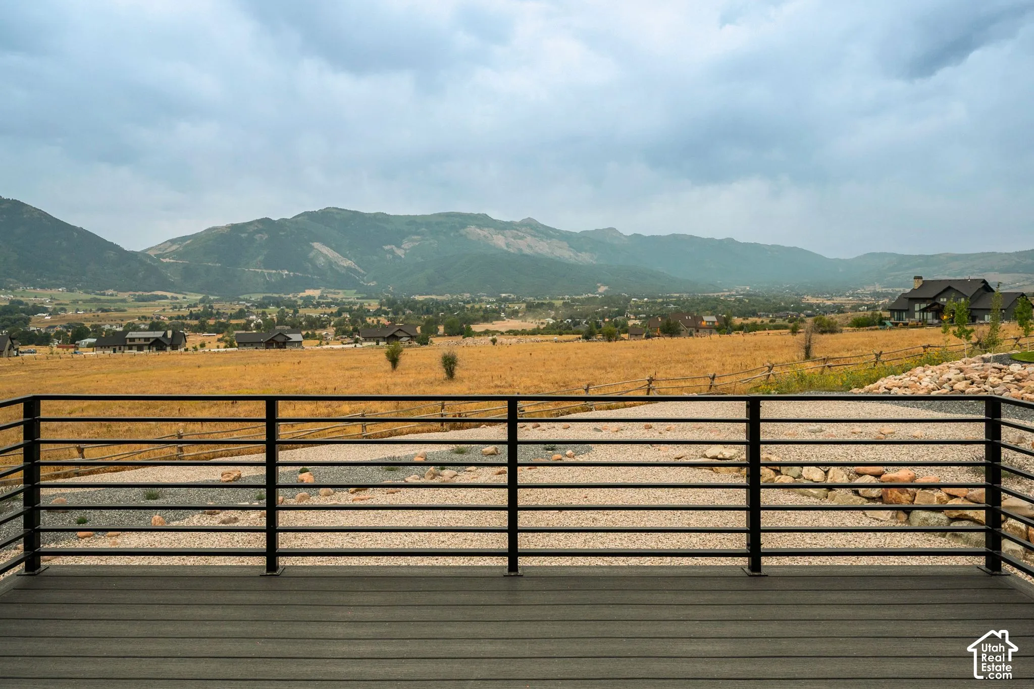 Expansive outdoor deck with composite decking and a black metal railing, overlooking a scenic mountain and valley landscape