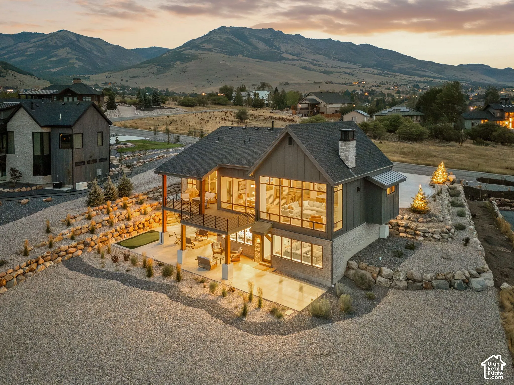 Multi-level modern residence featuring large format windows, a stone and vertical siding exterior, and a two-story covered outdoor living space