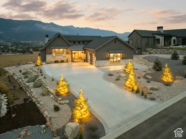 Exterior featuring board-and-batten siding with stone accents, a concrete driveway, and integrated outdoor lighting