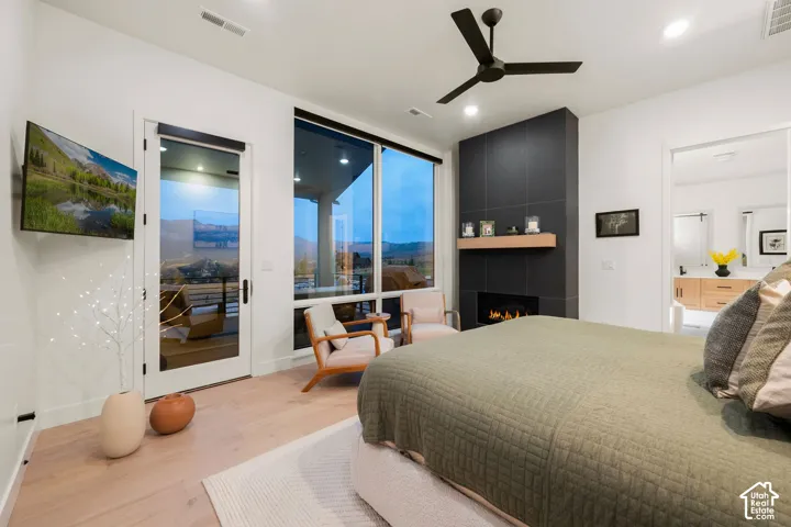 Primary Bedroom Suite with Expansive Glazed Doors and FireplaceThis light-filled bedroom features floor-to-ceiling glass doors opening to a covered exterior space, abundant natural light, and a striking black fireplace accent wall with integrated shelvi