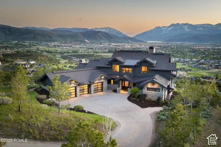 Multi-level residence featuring a stone and siding exterior, expansive driveway, and multiple garage doors