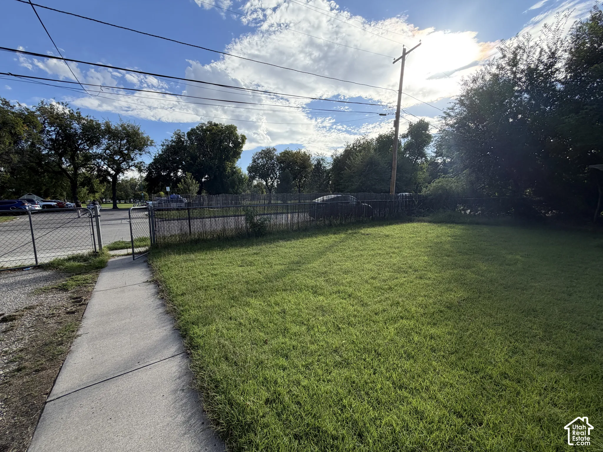 Expansive lawn with a concrete walkway, bordered by a chain-link fence