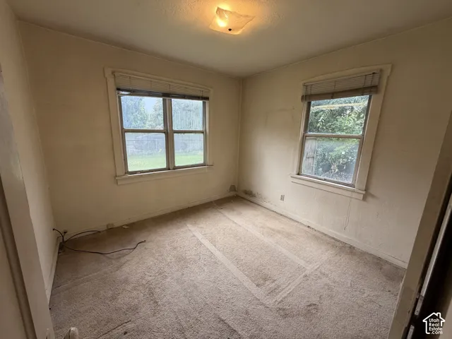 Recessed ceiling light fixture, two windows with horizontal blinds, and carpeted flooring