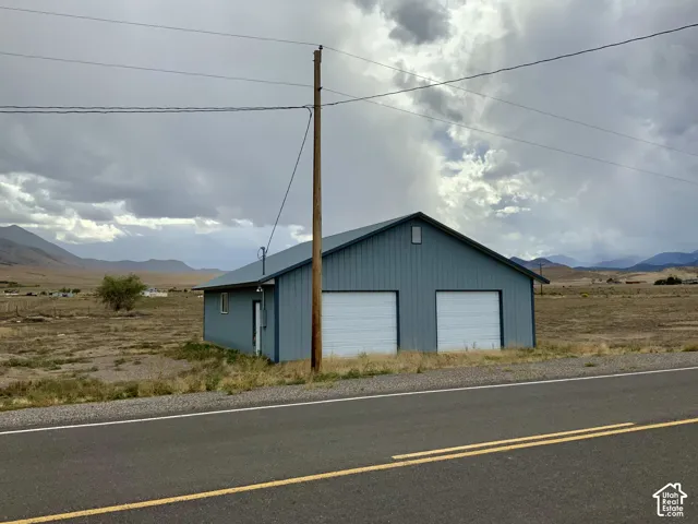 Metal-sided structure featuring a gabled roof and two white garage doors