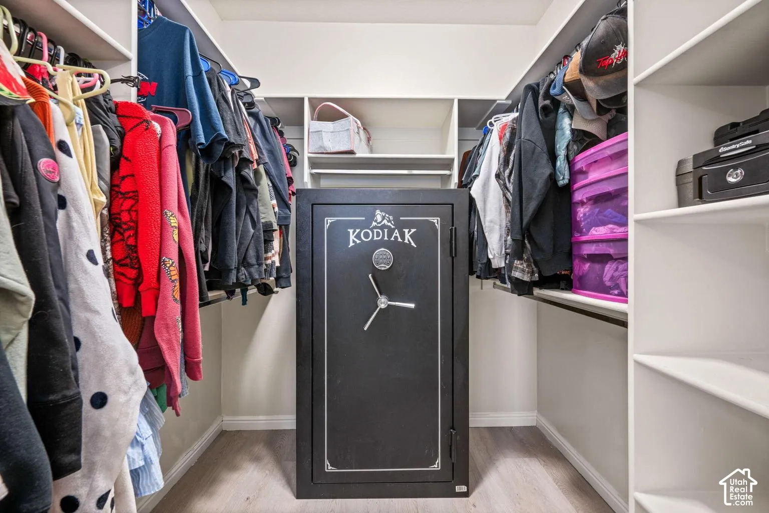 Walk-in closet with built-in shelving, hanging rods, and wood-finish flooring