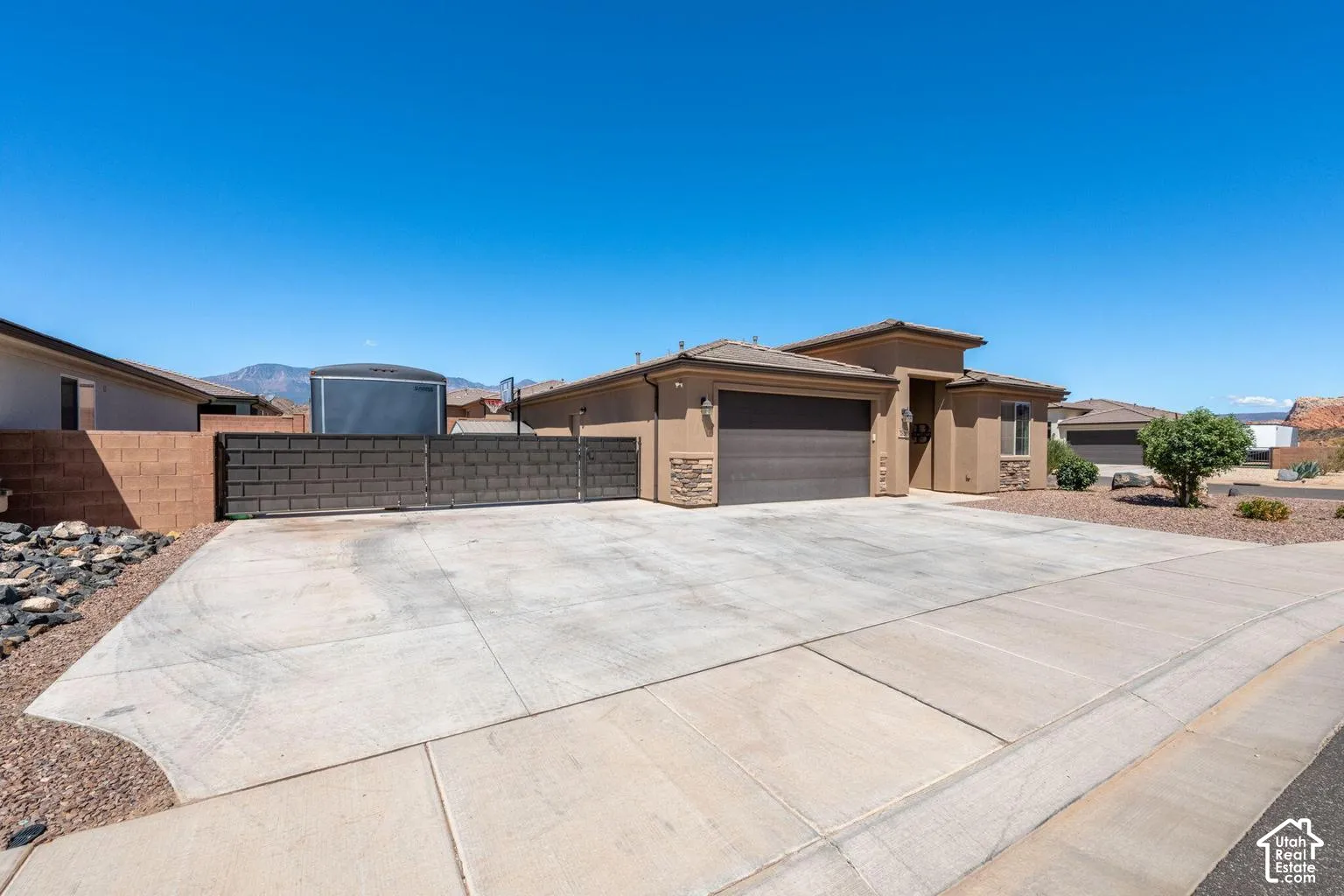 Stucco exterior with stone accents, an attached two-car garage, and a concrete driveway
