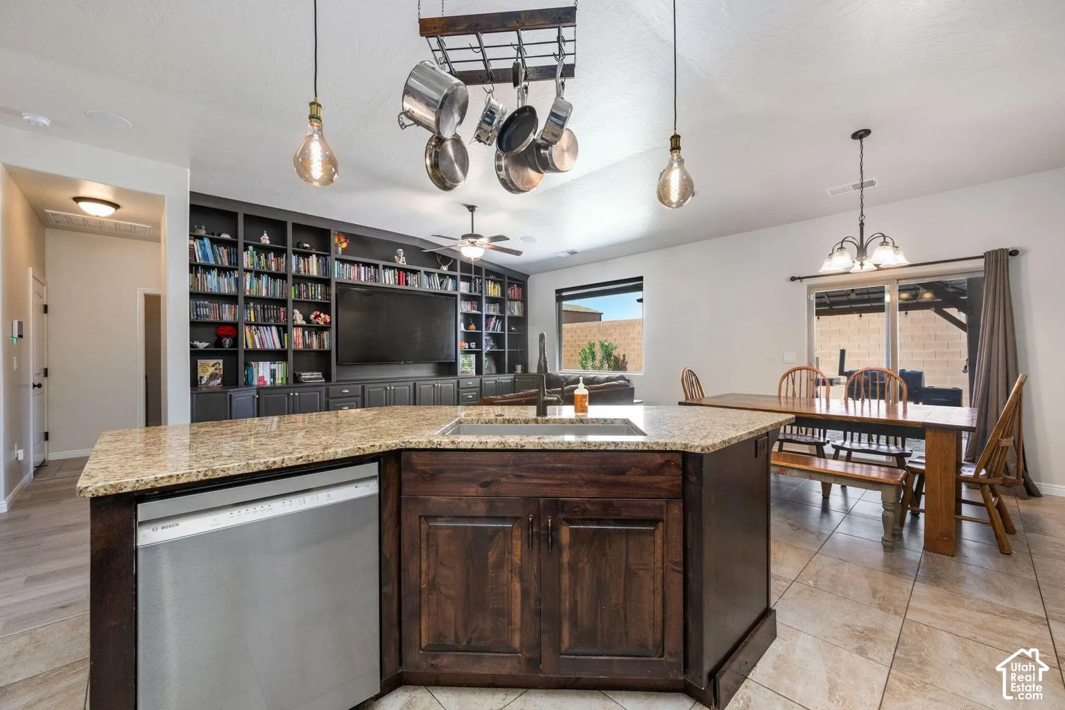Kitchen island with granite countertops, integrated stainless-steel dishwasher, and dark wood cabinetry