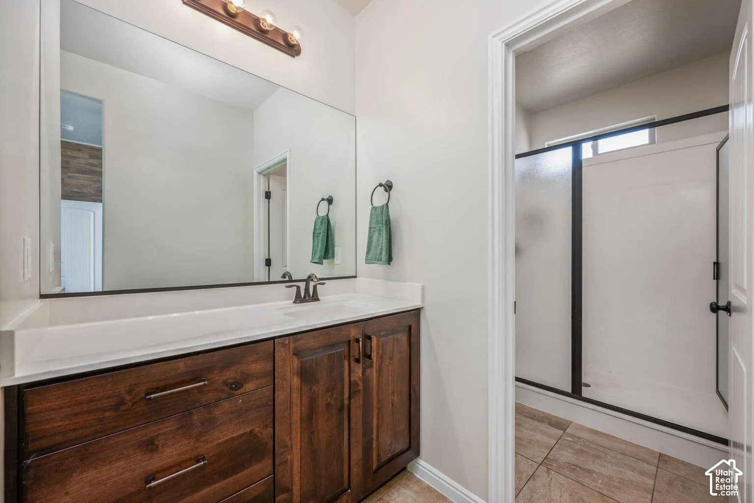 Primary bathroom featuring a wood-finish vanity with dual drawers, white quartz countertop, and an oversized framed mirror with integrated lighting
