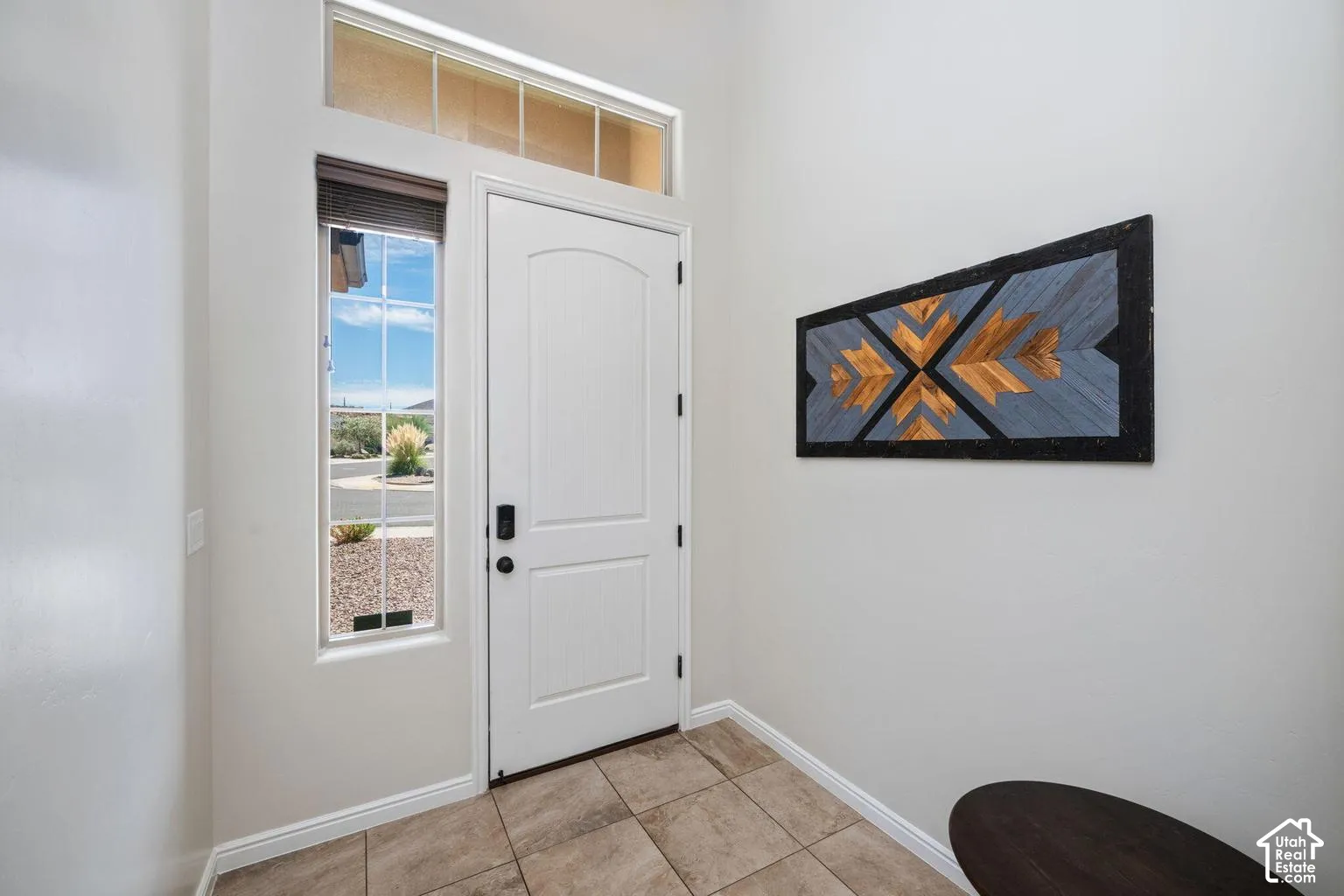 Entryway featuring a solid panel door, sidelight window, transom window, and tile flooring