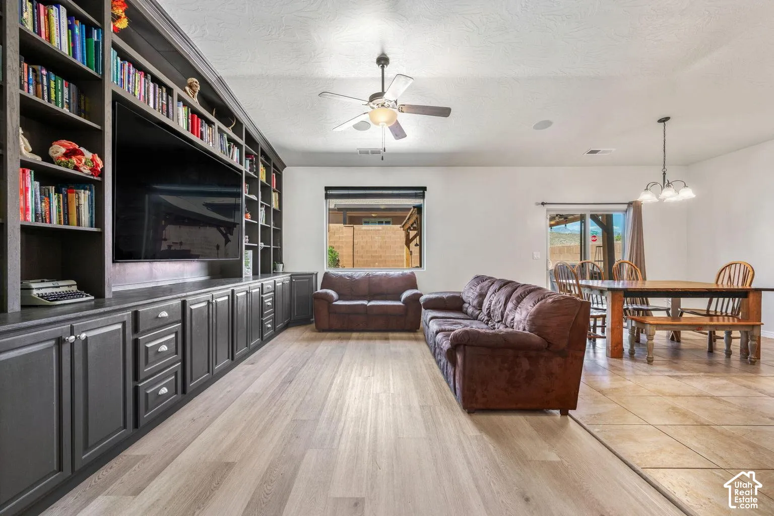 Custom built-in cabinetry with shelving, wood-finish flooring, ceiling fan, and sliding glass door