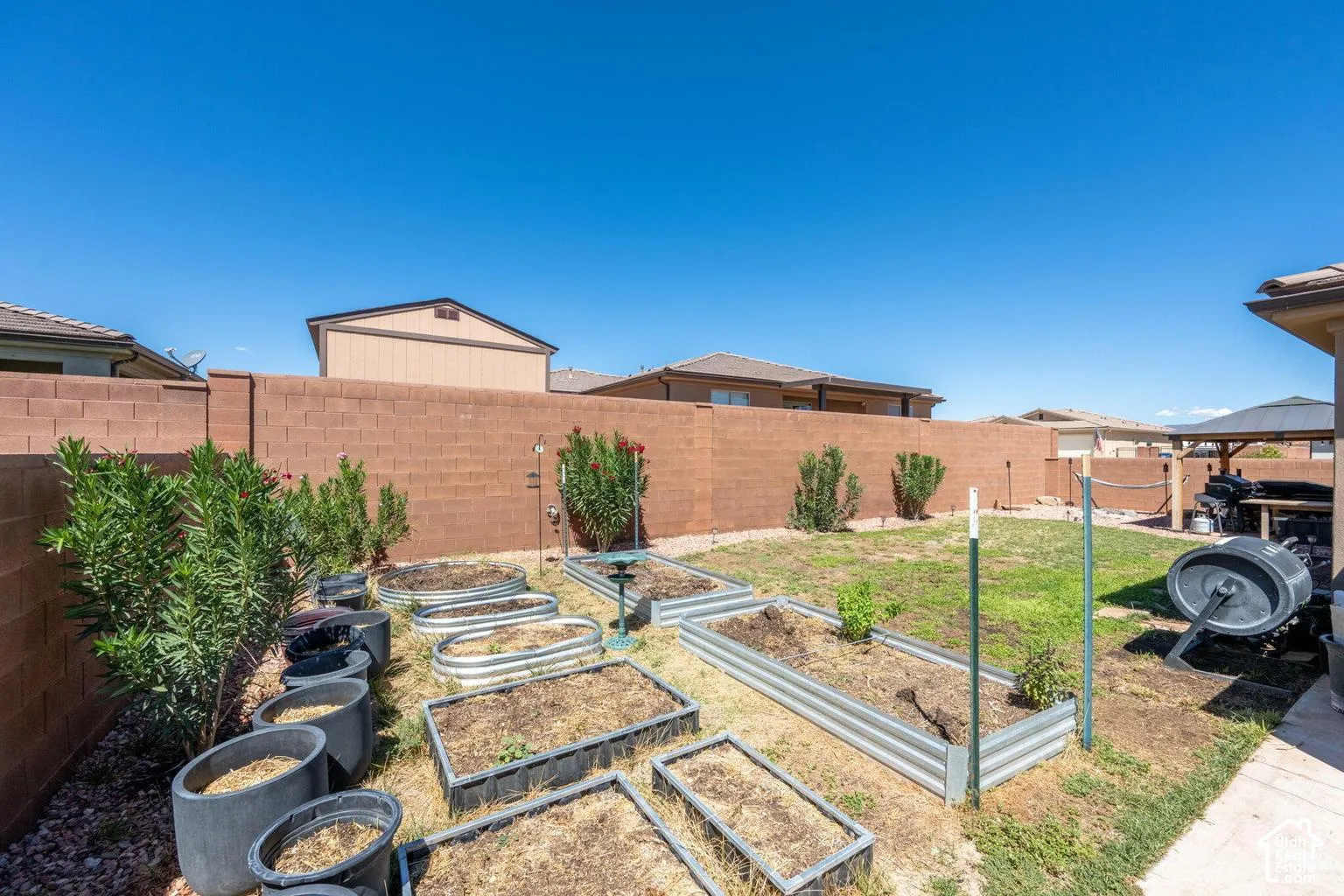Expansive backyard featuring a partial grass area, multiple raised garden beds, and mature shrubs