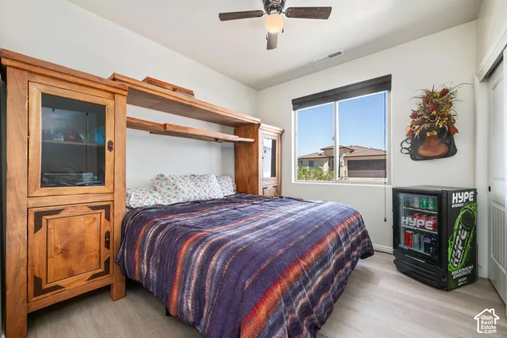 Light-toned wood-finish flooring, built-in wooden shelving, and a ceiling fan with integrated lighting