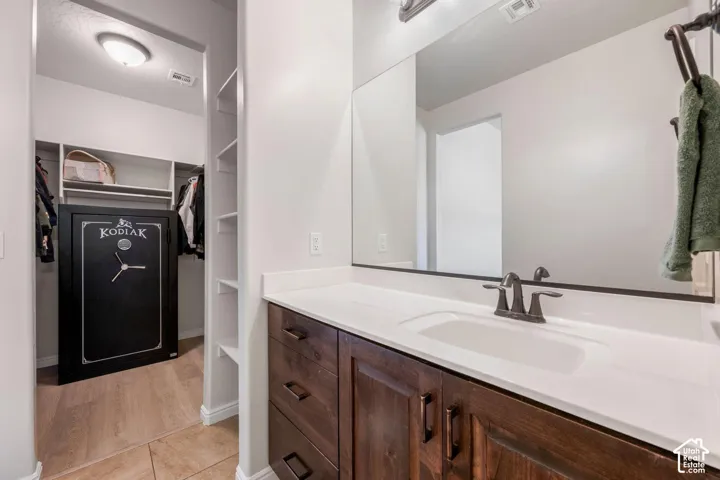 Vanity with a white countertop and integrated sink, bronze-finish faucet, and wood-finish cabinetry