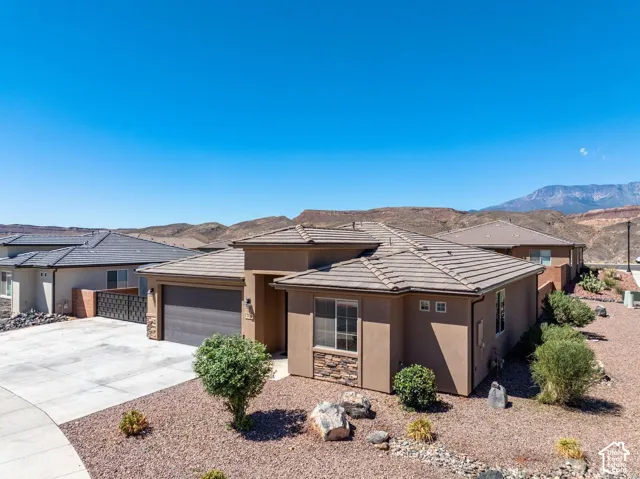 Exterior featuring a stucco finish, stone accents, a tile roof, an attached garage, and a concrete driveway