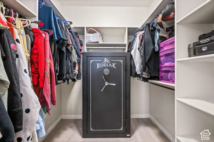 Walk-in closet with built-in shelving, hanging rods, and wood-finish flooring