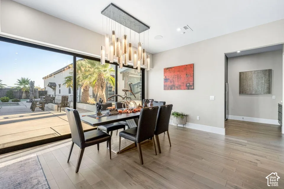 Dining area featuring wood-finish flooring, a contemporary chandelier, and a large sliding glass door