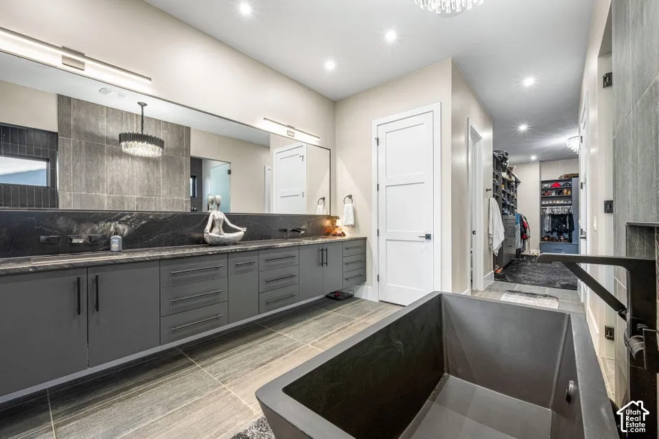 Freestanding soaking tub, wood-finish flooring, dual vanity with extensive storage, and recessed lighting