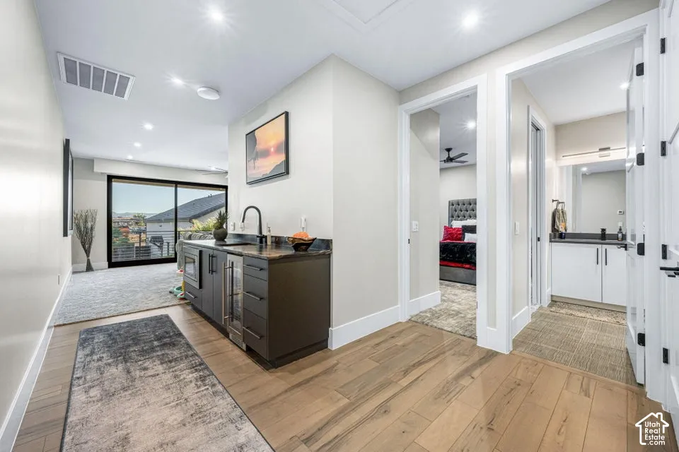 Wood-finish flooring, built-in wet bar with beverage refrigerator, recessed lighting, and sliding glass door