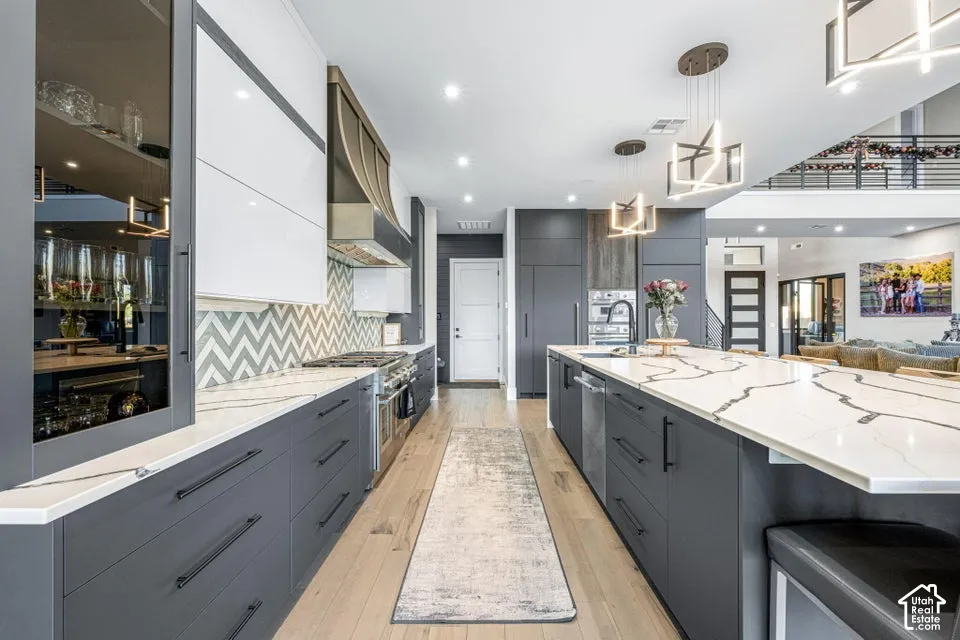 Gourmet kitchen with an expansive island, white countertops featuring dark veining, two-tone cabinetry, and wood-finish flooring