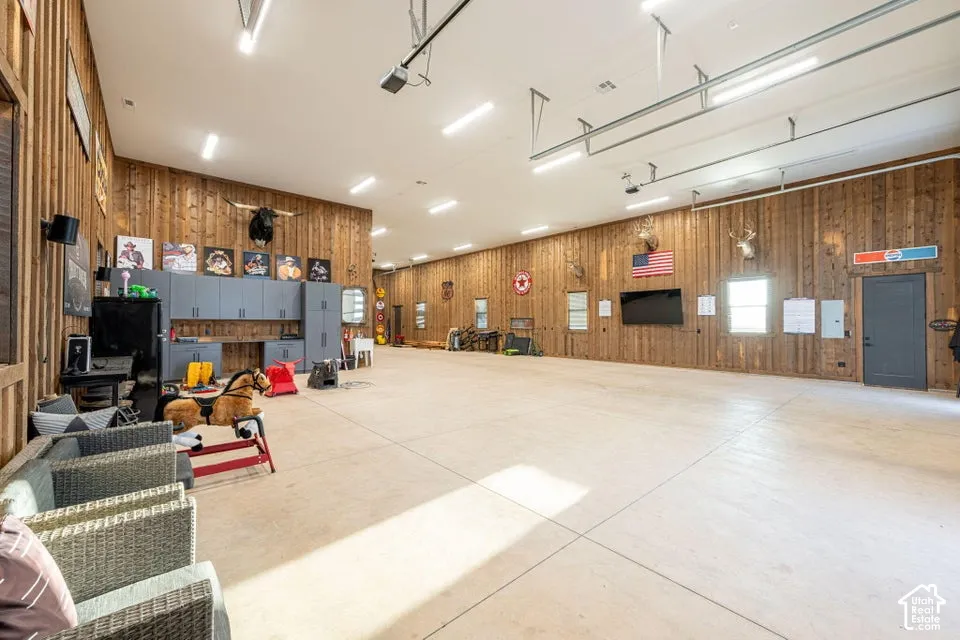 Spacious interior featuring wood paneling, extensive concrete flooring, and multiple overhead light fixtures