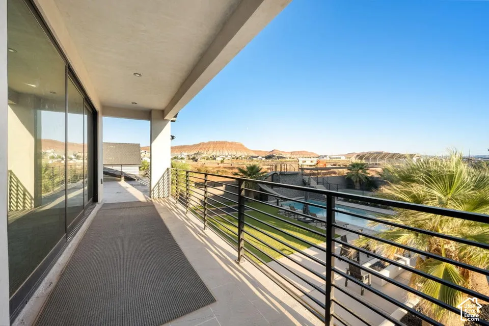 Expansive balcony featuring a black metal railing, large glass sliding doors, recessed lighting, and tiled flooring