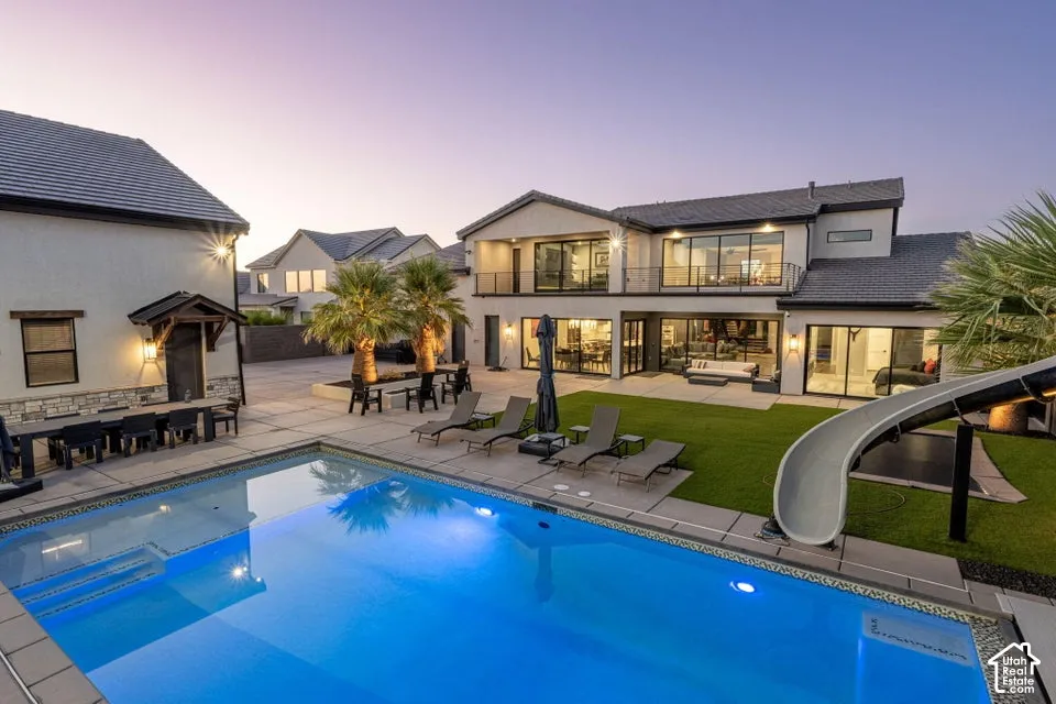 Contemporary exterior featuring a private swimming pool, expansive paved patio, and a manicured lawn
