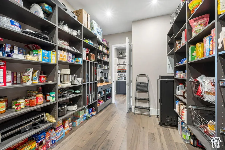 Expansive pantry featuring extensive built-in shelving, wood-finish flooring, and recessed lighting