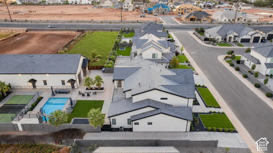 Modern stucco home with a dark gray tile roof, private swimming pool, dedicated sports court, and an expansive paved patio