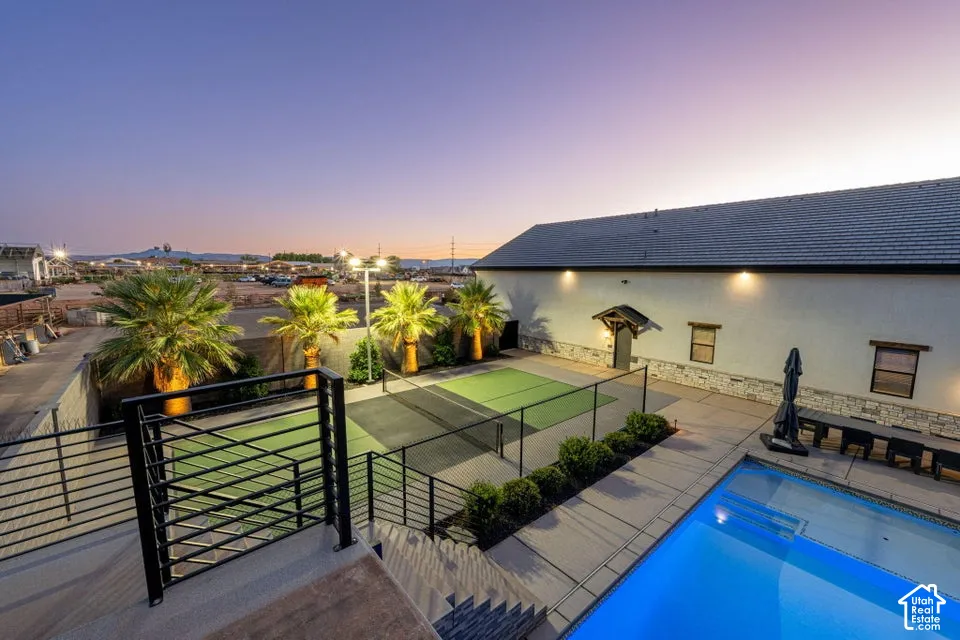 Outdoor area featuring a swimming pool, a pickleball court, and mature palm trees