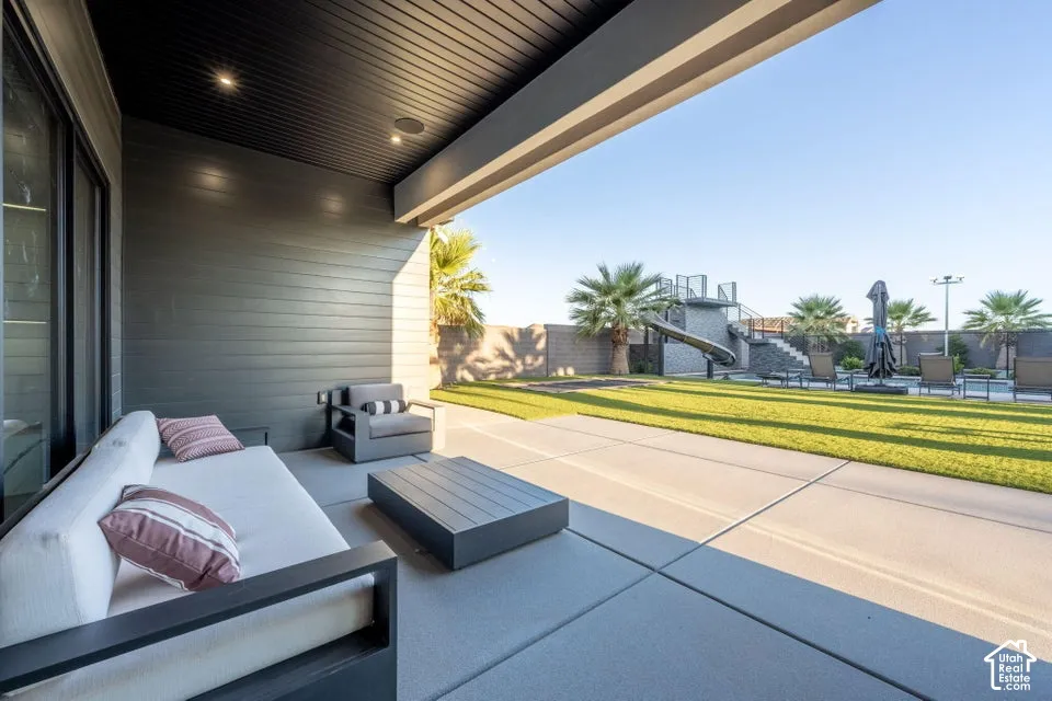 Expansive concrete patio with a covered outdoor living area featuring a plank ceiling with recessed lighting