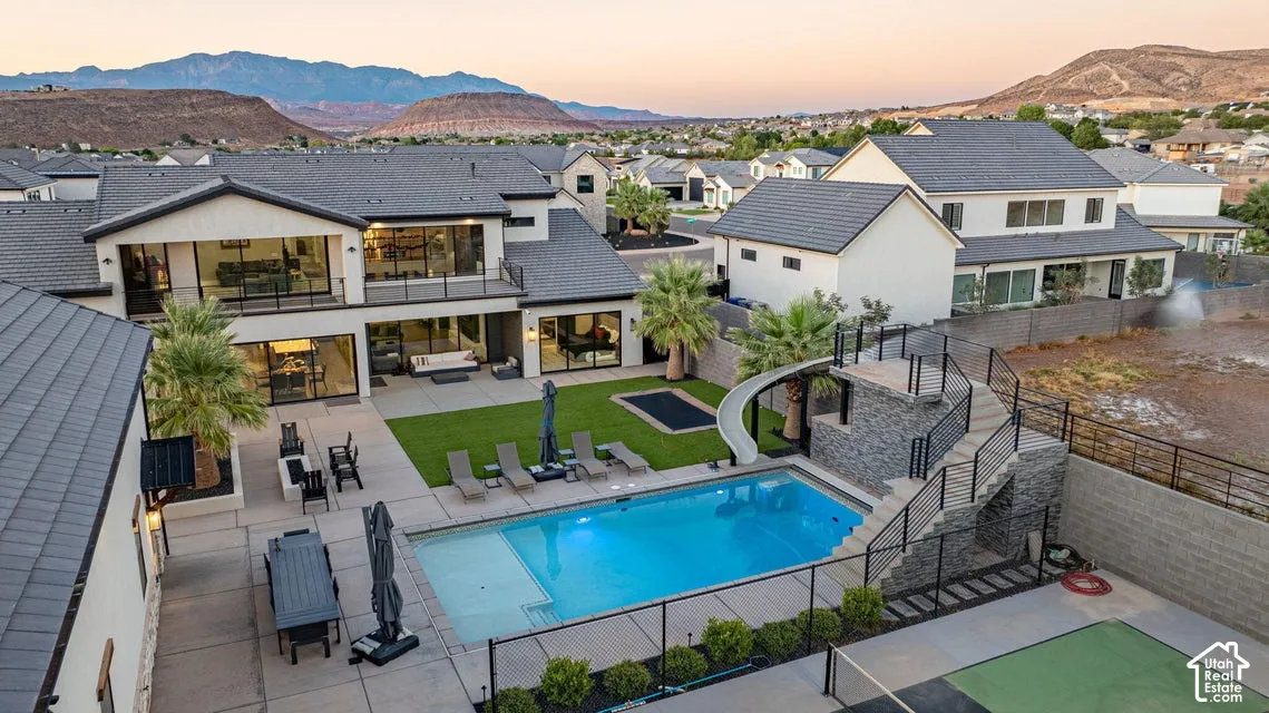 Expansive backyard featuring a swimming pool, integrated slide, large patio, and manicured lawn