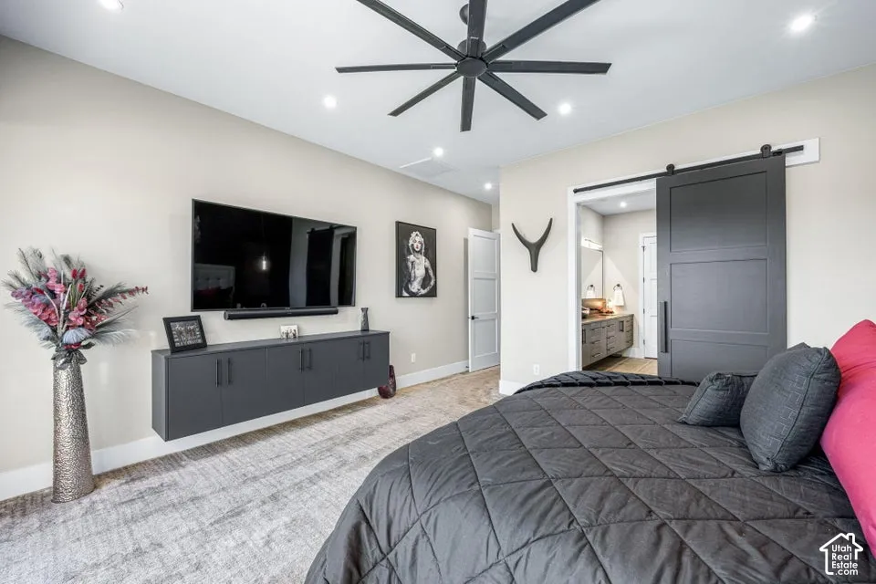Recessed ceiling lighting, floating media console, modern ceiling fan, dark barn door, and carpet flooring