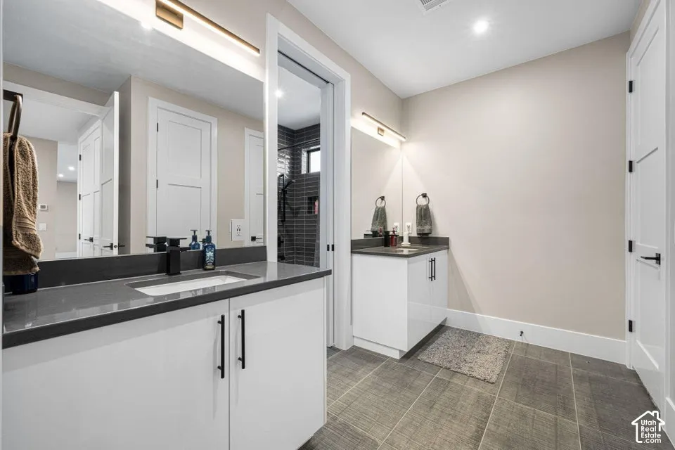 Dual vanity with undermount sinks, dark countertops, and modern cabinetry