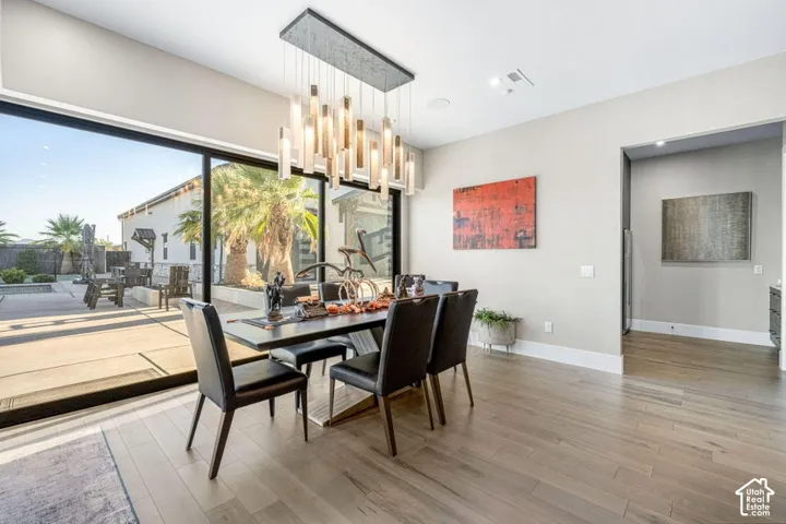 Dining area featuring wood-finish flooring, a contemporary chandelier, and a large sliding glass door