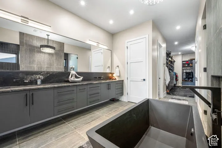 Freestanding soaking tub, wood-finish flooring, dual vanity with extensive storage, and recessed lighting