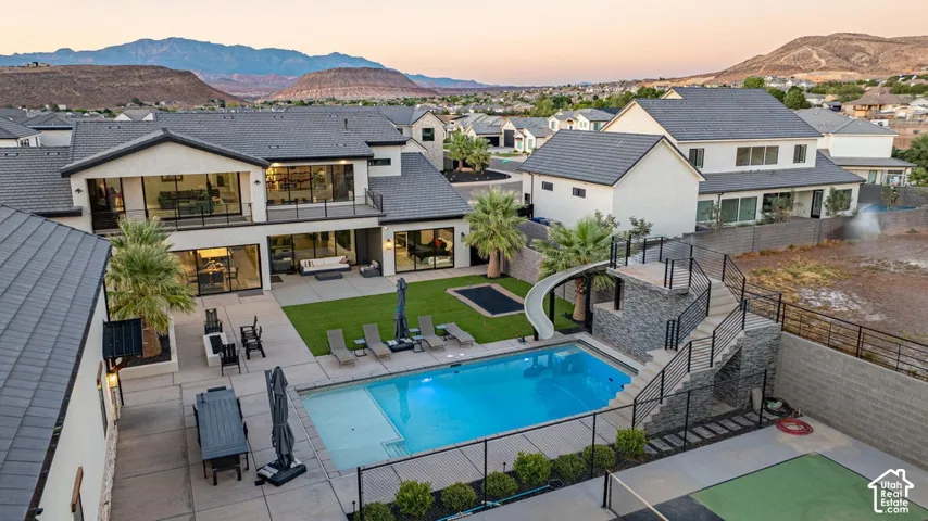 Expansive backyard featuring a swimming pool, integrated slide, large patio, and manicured lawn
