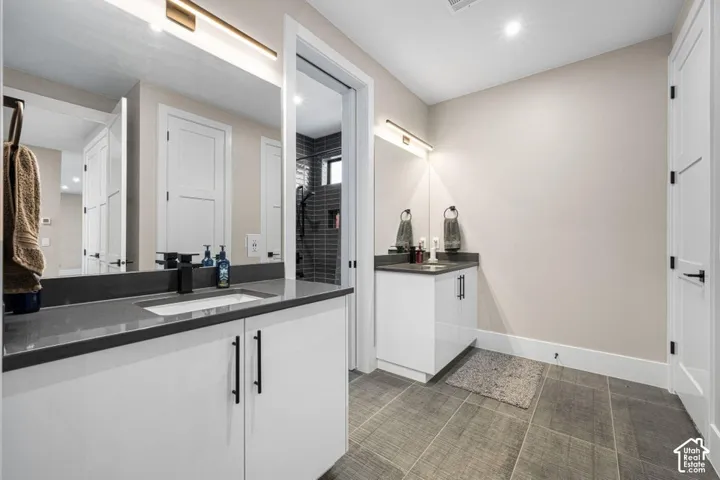 Dual vanity with undermount sinks, dark countertops, and modern cabinetry