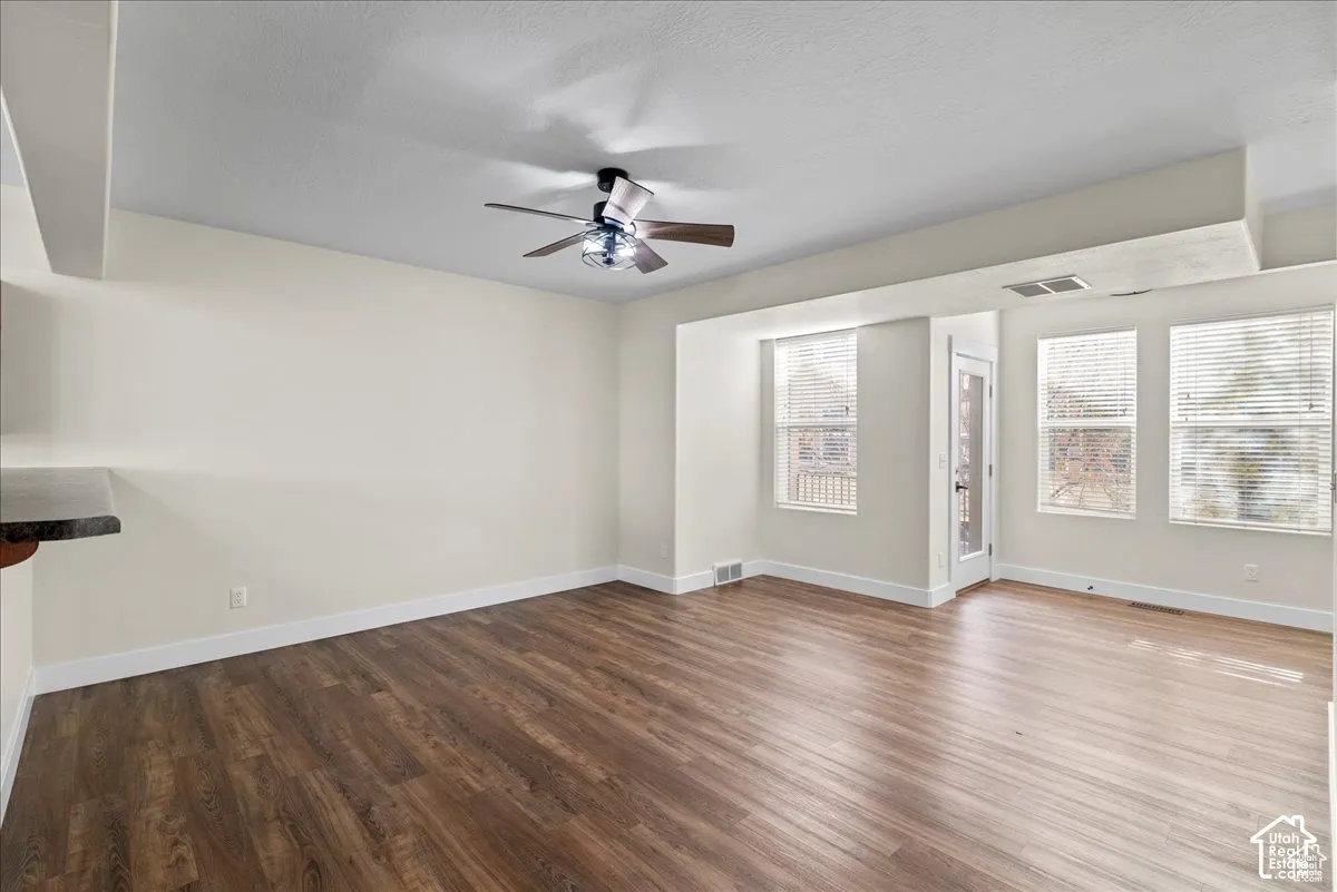 Wood-finish flooring, multiple windows, ceiling fan, white trim, and a built-in countertop