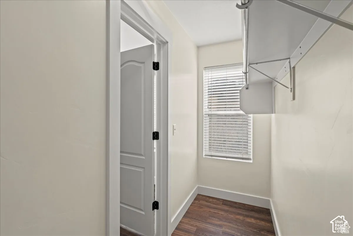 Master Walk-in closet with ample shelving, a window featuring blinds, and wood-finish flooring