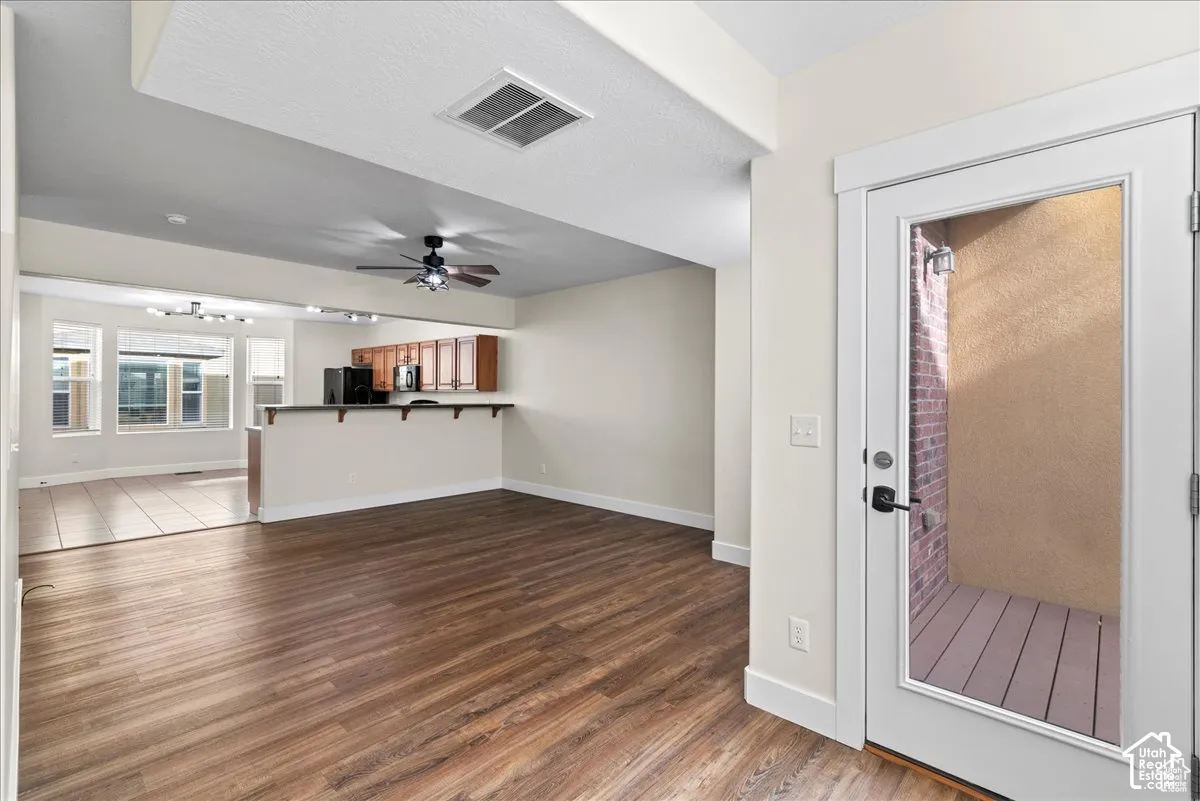 Open-concept living space featuring wood-finish flooring, a breakfast bar, and a ceiling fan