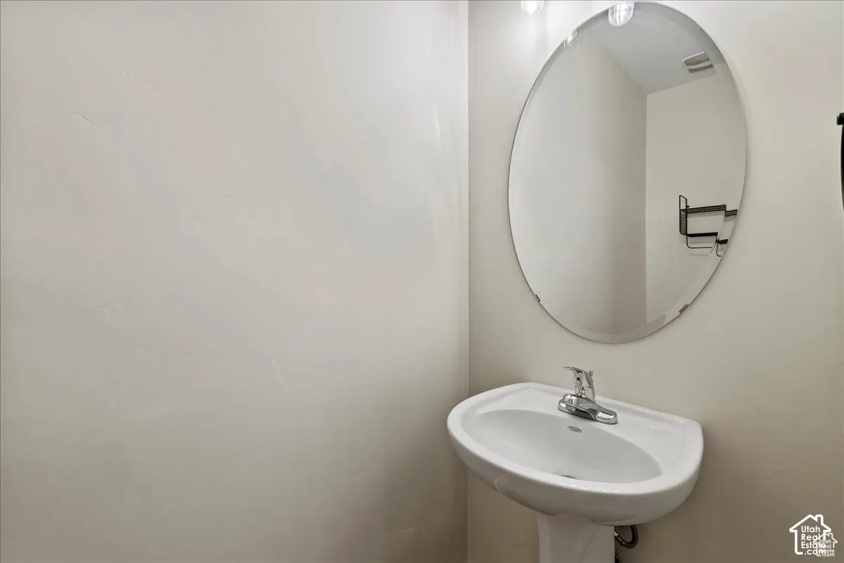 Pedestal sink with a polished chrome faucet and an oval wall mirror