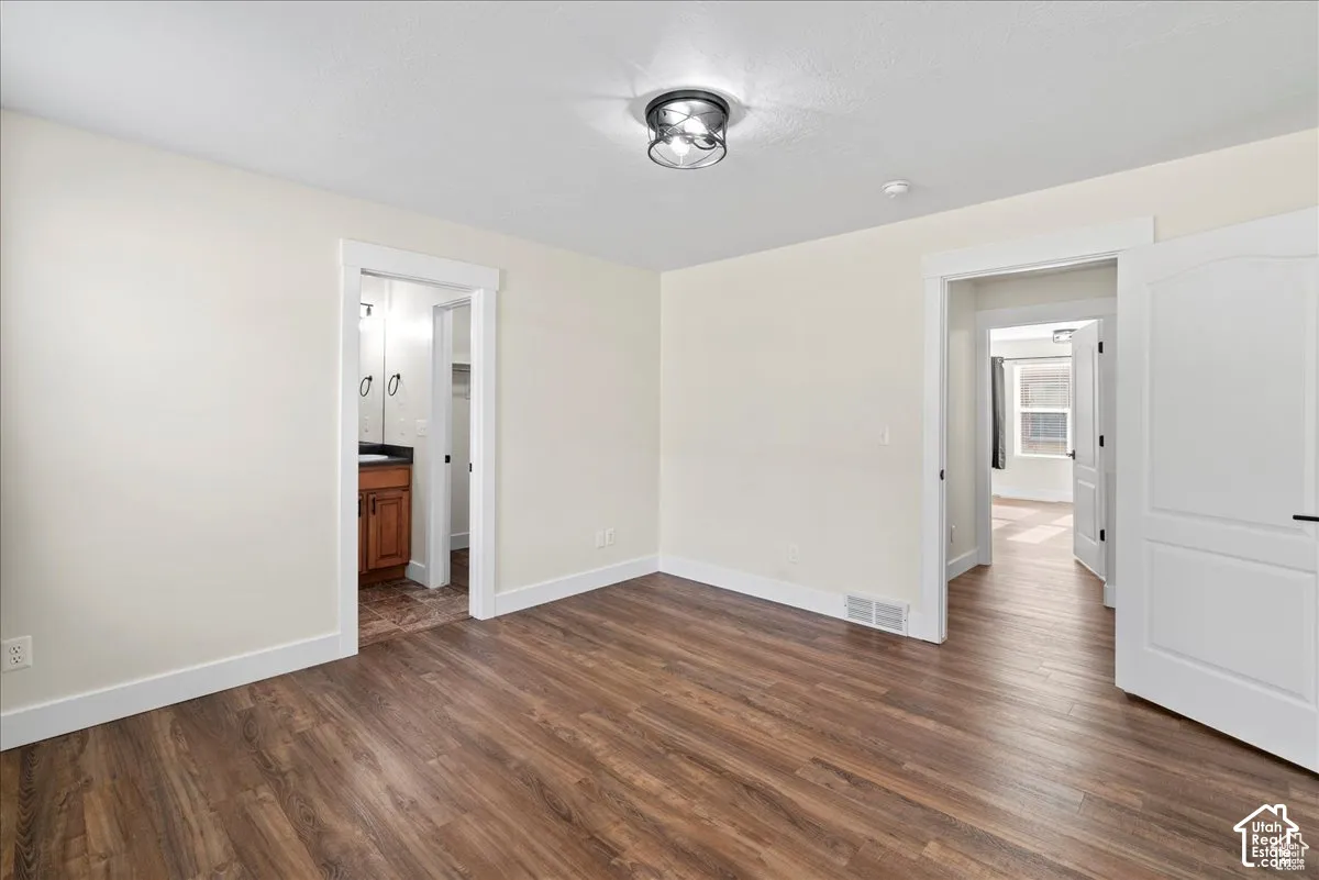 Wood-finish flooring, white walls, white trim, arch-top interior door, and flush-mount ceiling light fixture