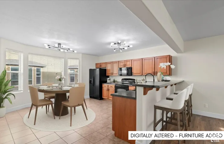 Kitchen featuring wood cabinetry, black appliances, a breakfast bar, and wood-finish flooring