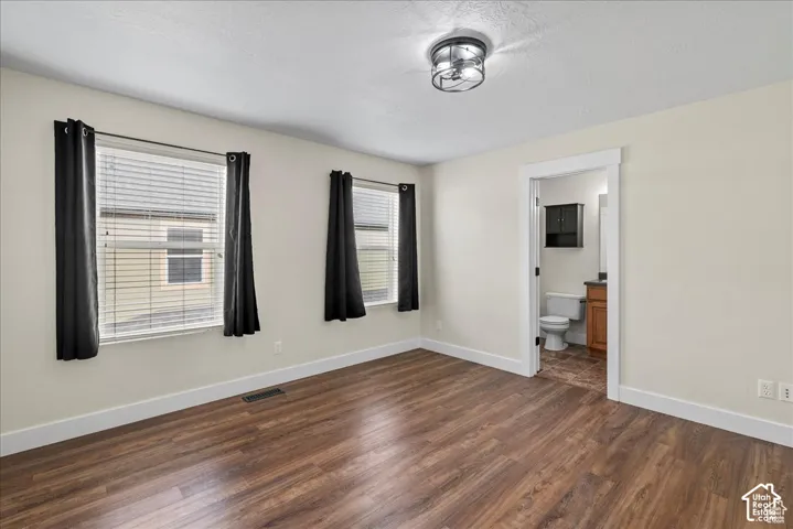 Wood-finish flooring, multiple windows, a ceiling-mounted light fixture, and white trim
