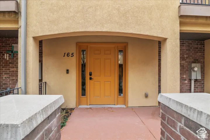 Stucco exterior facade with an arched entryway, featuring a panelized front door with sidelights, and a concrete paver path