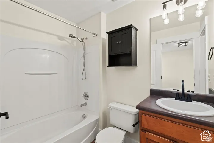 Built-in bathtub with shower, wood-finish vanity with countertop, oval undermount sink, and wall-mounted mirror
