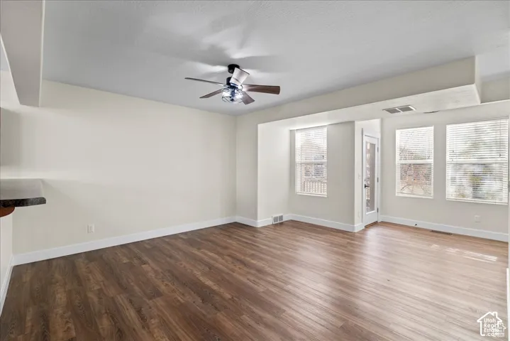 Wood-finish flooring, multiple windows, ceiling fan, white trim, and a built-in countertop