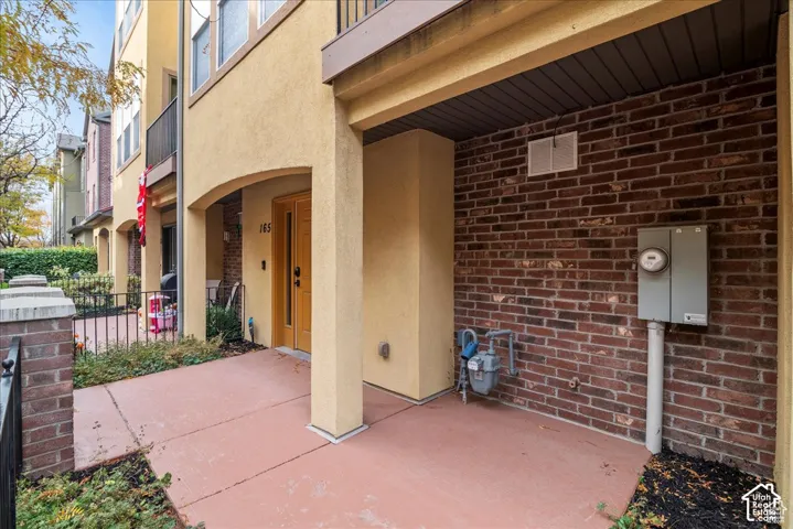 Stucco exterior with an arched entryway, brick accent wall, and a wood-finish front door with glass inserts
