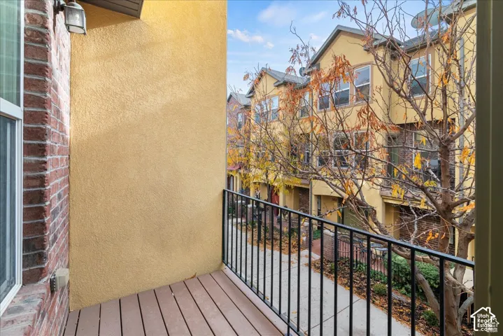Balcony with wood-finish flooring, stucco exterior, and brick accents